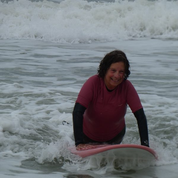 une dame qui glisse allongé avec une planche de surf dans la mousse.