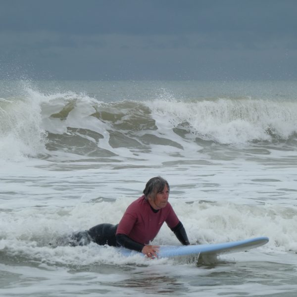 une dame qui glisse allongé avec une planche de surf dans la mousse.